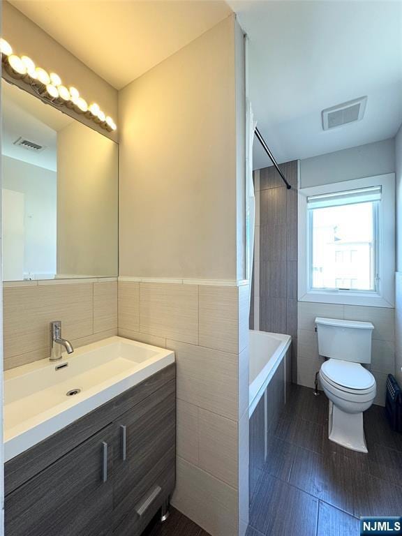 bathroom with visible vents, toilet, shower / tub combination, and tile walls