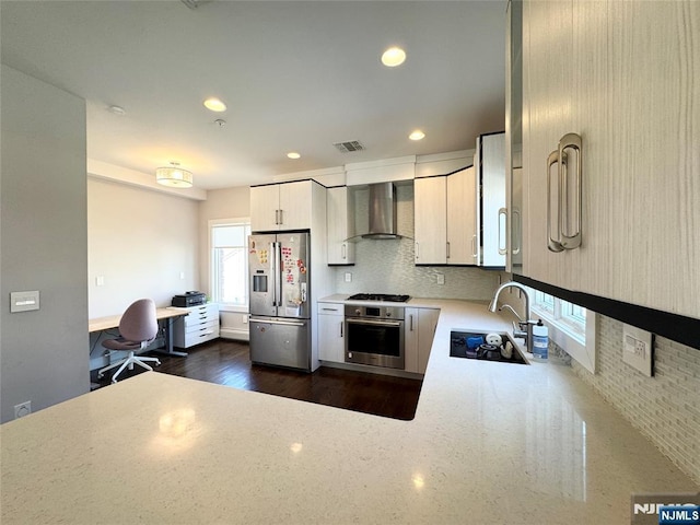 kitchen featuring recessed lighting, stainless steel appliances, a sink, decorative backsplash, and wall chimney exhaust hood