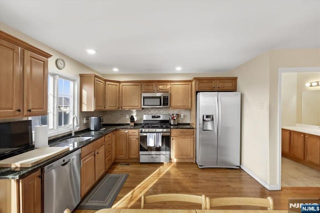 kitchen featuring tasteful backsplash, appliances with stainless steel finishes, light wood-style floors, a sink, and recessed lighting