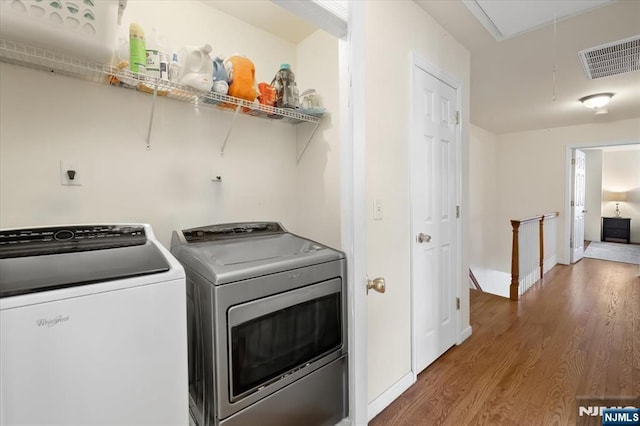 washroom featuring visible vents, attic access, wood finished floors, laundry area, and independent washer and dryer