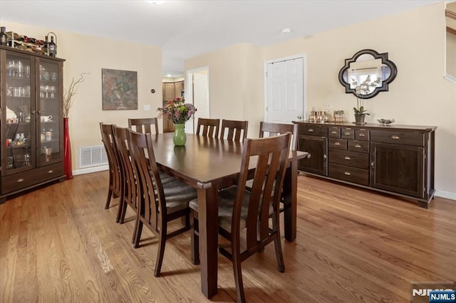 dining space featuring light wood-type flooring, visible vents, and baseboards