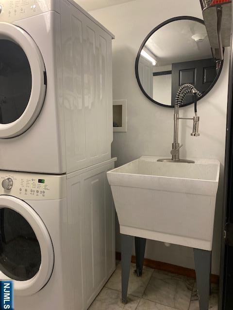 laundry room with stacked washer and dryer, a sink, and laundry area