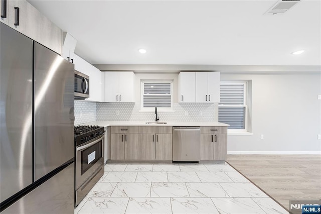 kitchen with marble finish floor, light countertops, visible vents, appliances with stainless steel finishes, and a sink