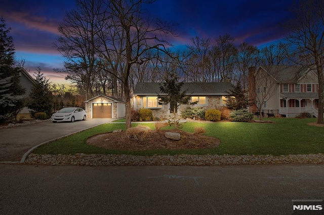 view of front of home featuring aphalt driveway, an outbuilding, an attached garage, and a front lawn