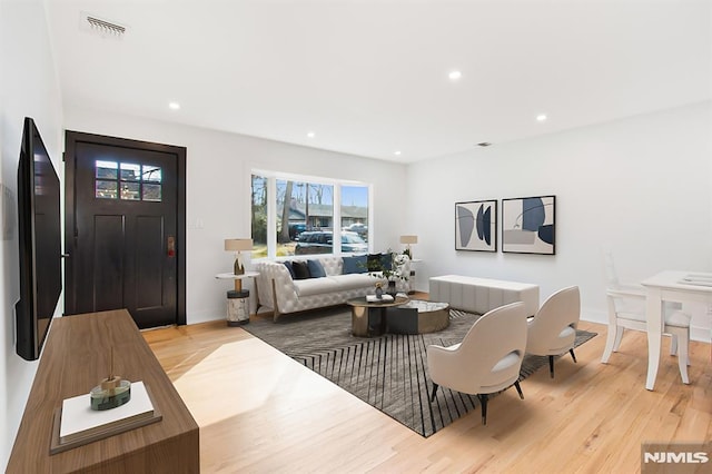 living room featuring light wood-style flooring, visible vents, and recessed lighting