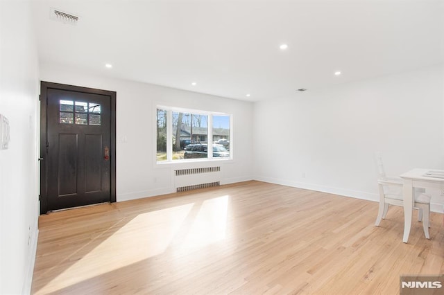 foyer entrance with light wood finished floors, radiator heating unit, visible vents, and recessed lighting