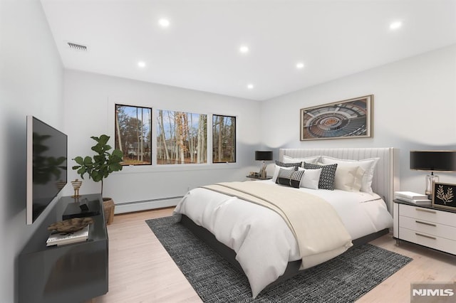 bedroom with a baseboard heating unit, light wood-type flooring, visible vents, and recessed lighting