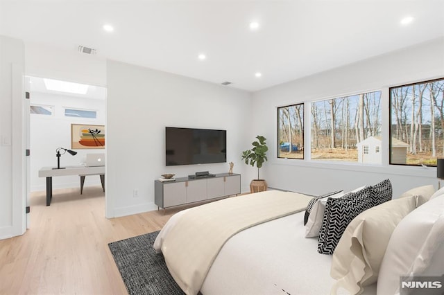 bedroom with baseboards, light wood finished floors, visible vents, and recessed lighting