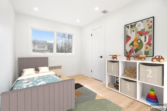 bedroom with radiator heating unit, visible vents, wood finished floors, and recessed lighting