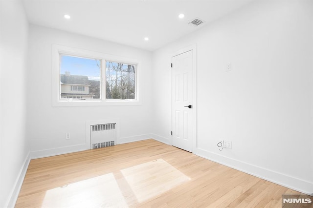 spare room with recessed lighting, wood finished floors, visible vents, and radiator