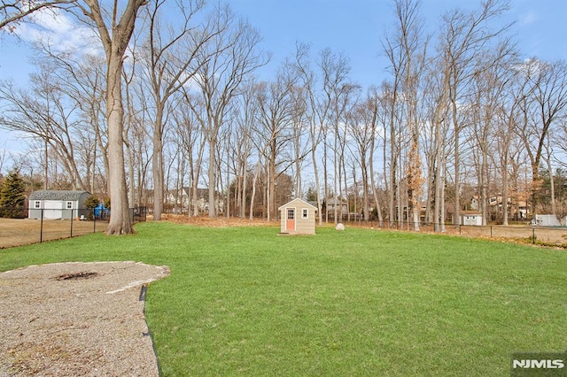 view of yard featuring a storage shed, an outdoor structure, and fence