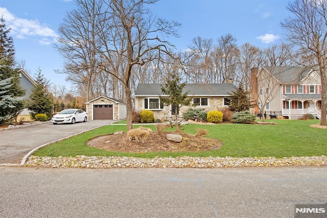 view of front facade with stone siding, a front lawn, aphalt driveway, and an outbuilding