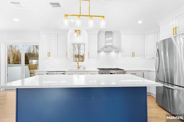 kitchen with stainless steel appliances, light countertops, visible vents, and wall chimney exhaust hood