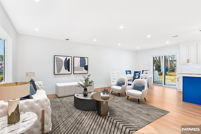 living room featuring baseboards, light wood finished floors, visible vents, and recessed lighting