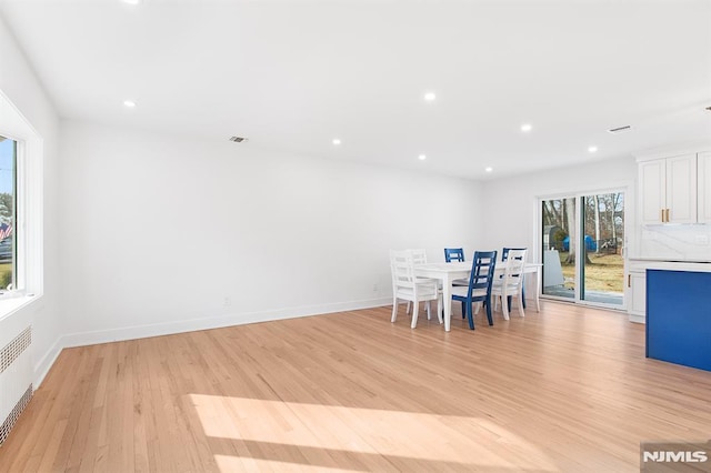 unfurnished dining area featuring baseboards, recessed lighting, light wood-type flooring, and radiator