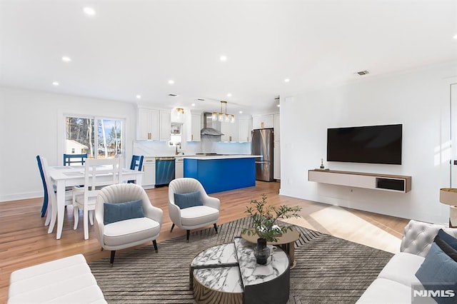 living room with light wood-type flooring, visible vents, and recessed lighting