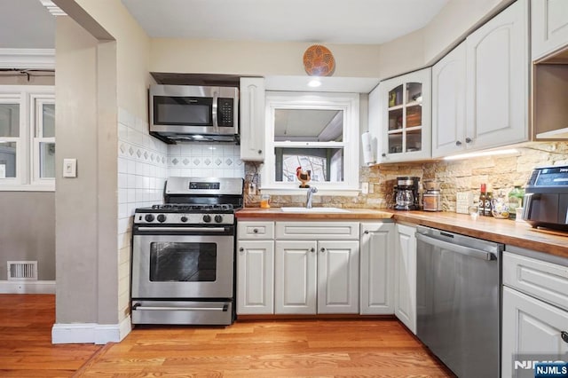 kitchen with butcher block counters, visible vents, appliances with stainless steel finishes, and decorative backsplash