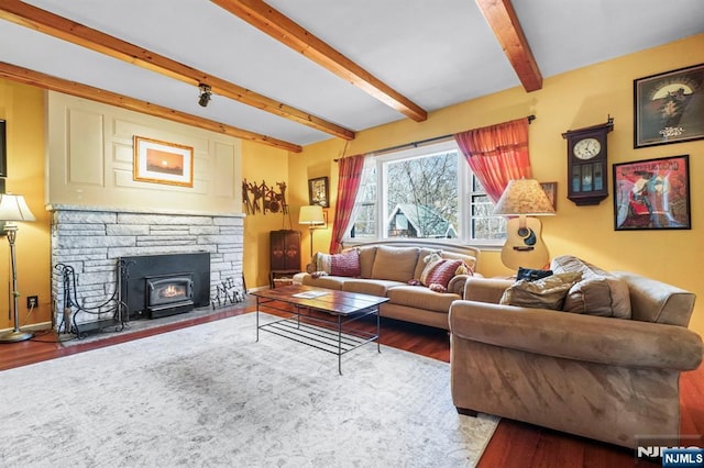 living room with a fireplace, beamed ceiling, baseboards, and wood finished floors