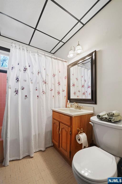 full bathroom with curtained shower, vanity, and toilet