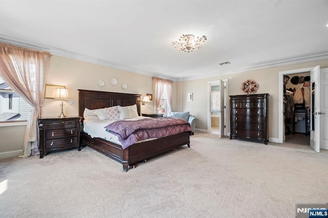 carpeted bedroom featuring ensuite bath, baseboards, a spacious closet, and ornamental molding