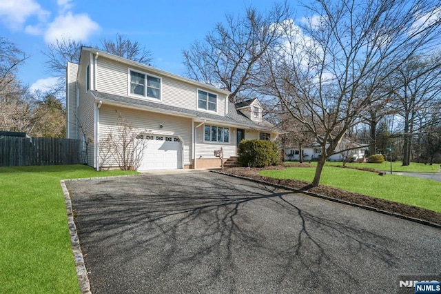 view of front of house with driveway, a garage, fence, and a front lawn