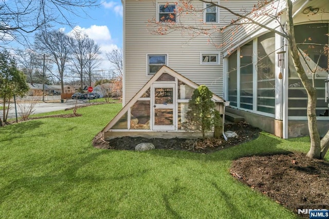 rear view of property with a sunroom and a lawn