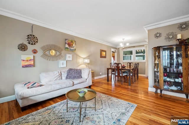 living room featuring a chandelier, baseboards, wood finished floors, and crown molding