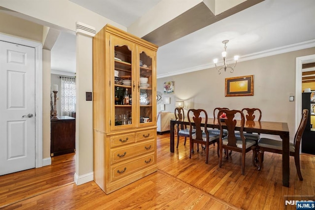 dining space with baseboards, a notable chandelier, crown molding, and light wood finished floors