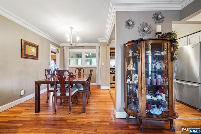 dining area with ornamental molding, a chandelier, and light wood-style floors