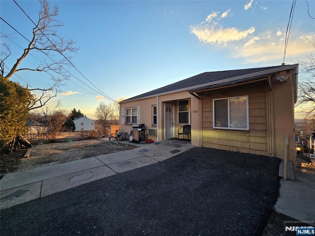 view of front of home featuring a shingled roof, a patio, and fence