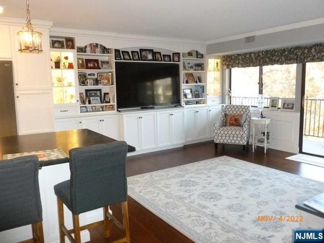 living area featuring ornamental molding, dark wood-style flooring, visible vents, and a notable chandelier