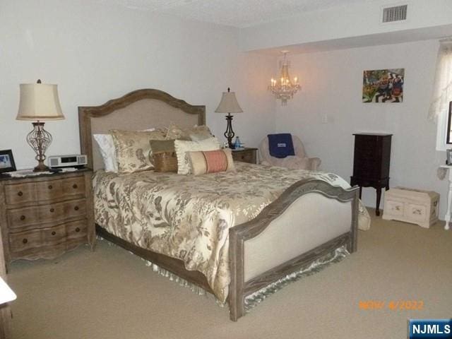 carpeted bedroom featuring a chandelier and visible vents