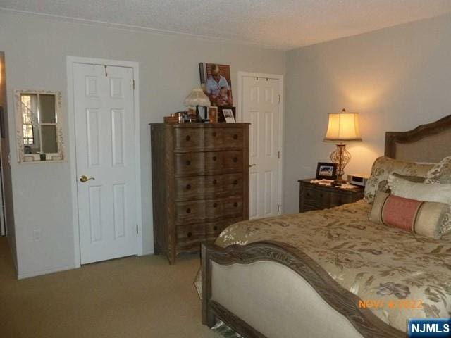 bedroom with light colored carpet and a textured ceiling