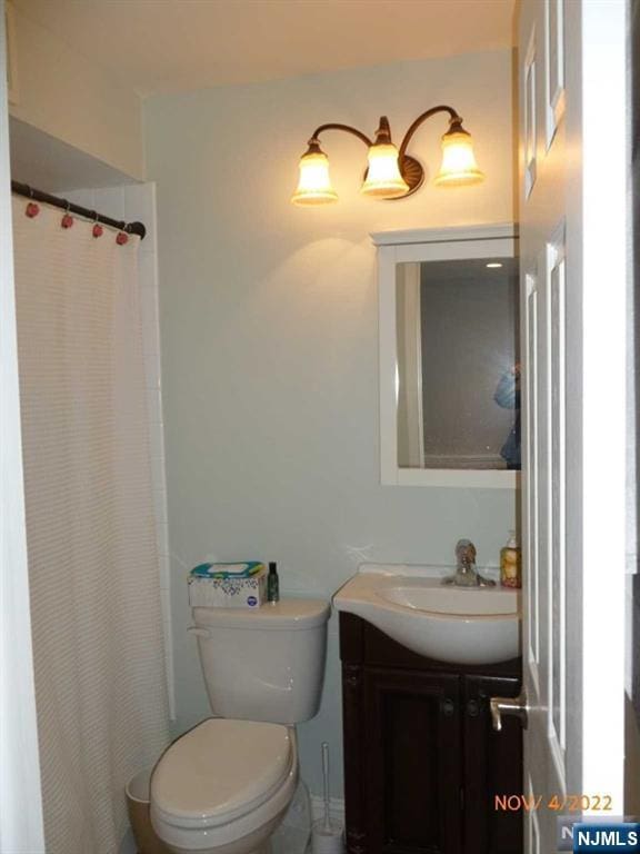 bathroom with toilet, a shower with shower curtain, and vanity