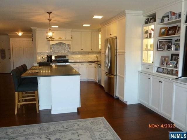 kitchen featuring white cabinets, dark countertops, dark wood-style flooring, hanging light fixtures, and stainless steel appliances