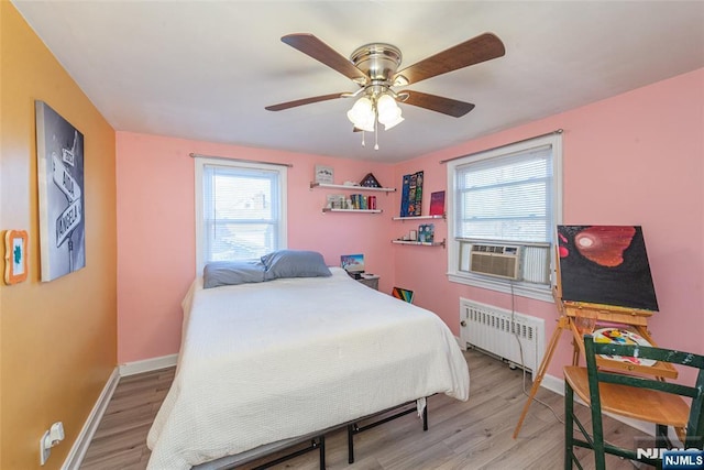 bedroom featuring radiator, light wood-style flooring, baseboards, and cooling unit