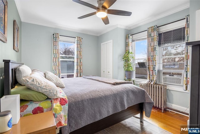 bedroom featuring ornamental molding, a ceiling fan, wood finished floors, cooling unit, and radiator