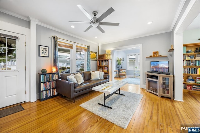 living room featuring light wood-style flooring, a fireplace, and ornamental molding