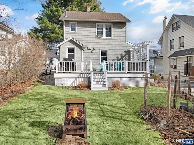 rear view of house featuring a wooden deck, a lawn, a shingled roof, and fence