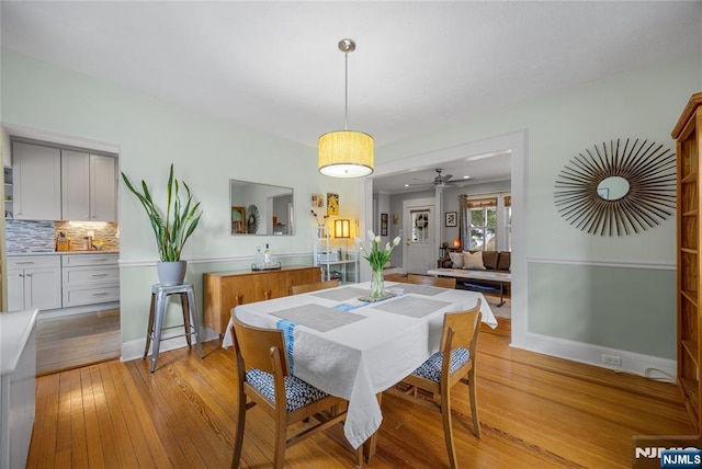 dining room with baseboards, light wood finished floors, and ceiling fan