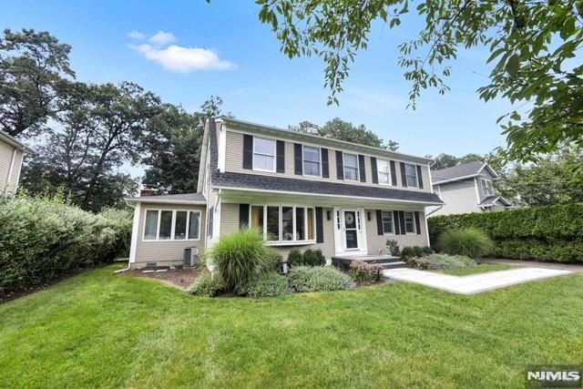 view of front of house with cooling unit, a chimney, and a front yard