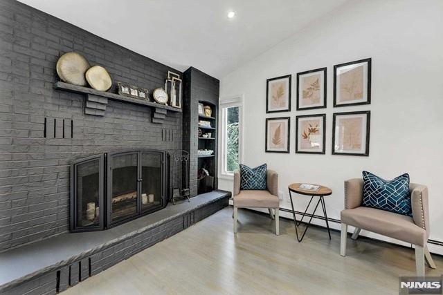 sitting room featuring a brick fireplace, lofted ceiling, and wood finished floors