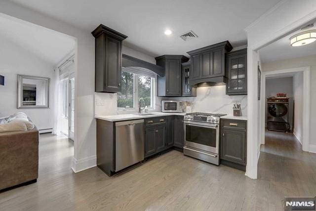 kitchen with visible vents, a sink, appliances with stainless steel finishes, light countertops, and washer / dryer