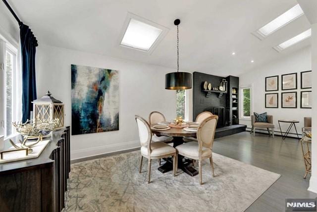 dining room with wood finished floors, baseboards, recessed lighting, lofted ceiling with skylight, and baseboard heating