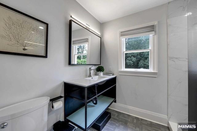 full bath featuring baseboards, toilet, walk in shower, and vanity