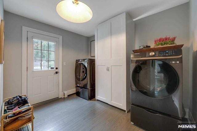 washroom with light wood-style flooring, cabinet space, separate washer and dryer, a baseboard radiator, and baseboards