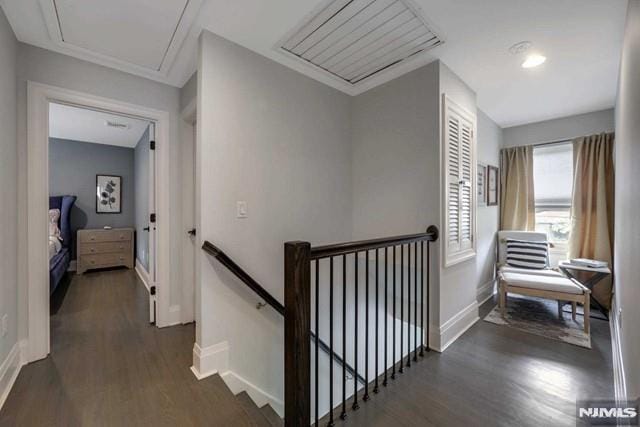 hallway featuring attic access, an upstairs landing, dark wood-type flooring, and baseboards