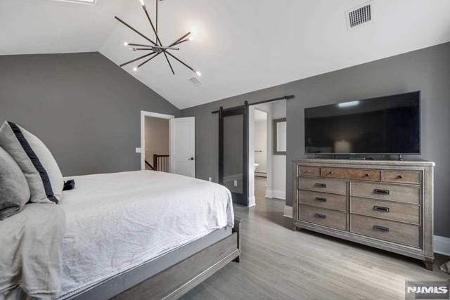 bedroom with visible vents, baseboards, a chandelier, lofted ceiling, and light wood-style floors