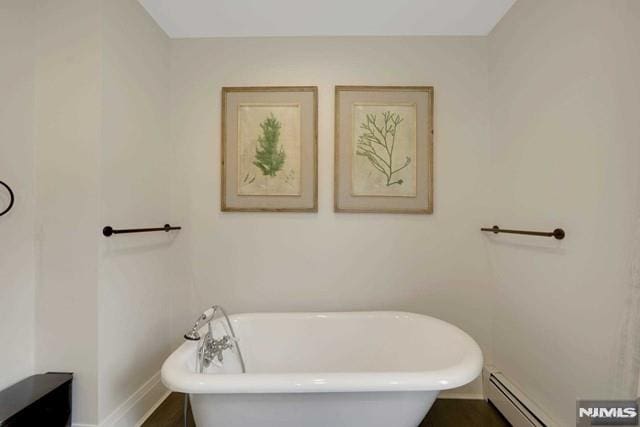 full bath featuring a soaking tub, baseboards, and baseboard heating