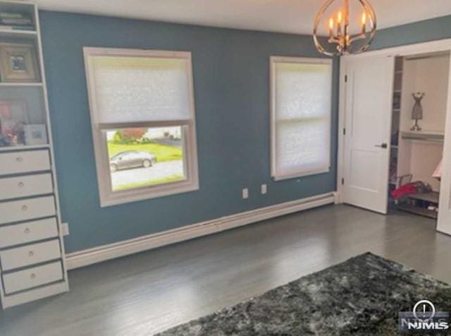 bedroom featuring a notable chandelier, wood finished floors, and baseboards